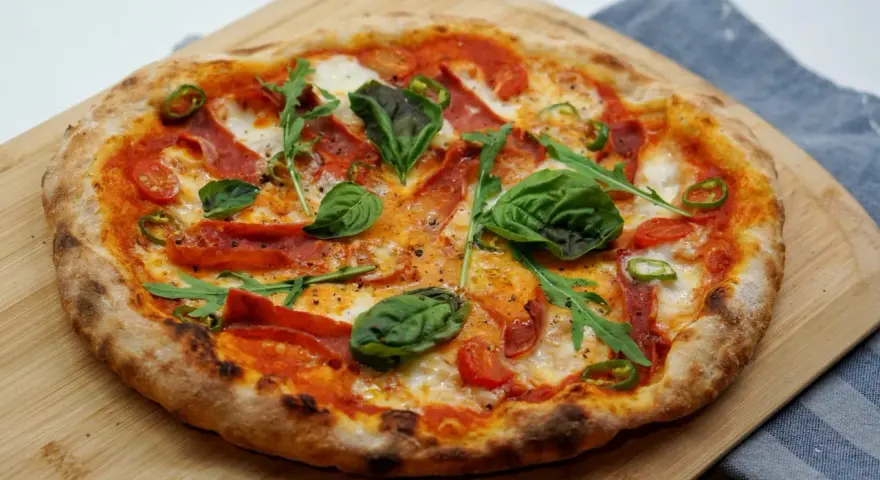 Pyszna pizza z rukolą, pomidorkami, papryczką i salami. Idealne składniki na pizzę, które zachwycą każdego smakosza.
