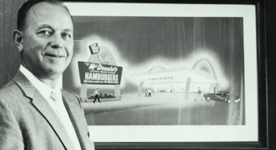 Ray Kroc, który wymyślił McDonald's, stoi obok obrazu przedstawiającego pierwszy lokal.