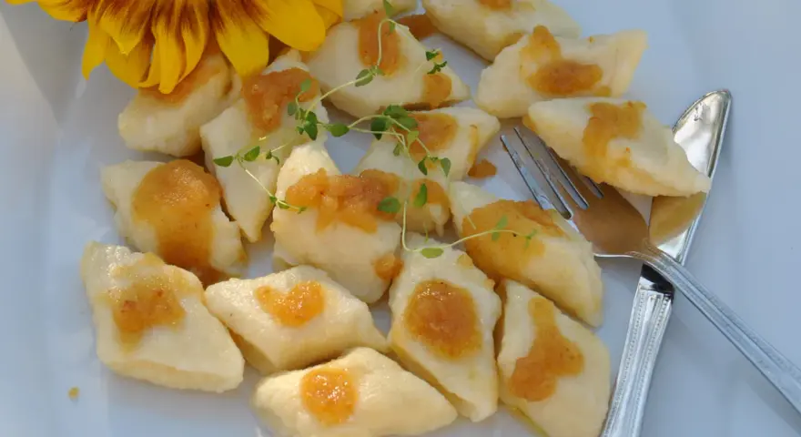 Pyszne, leniwe pierogi z sosem i gałązką tymianku, obok słonecznik.