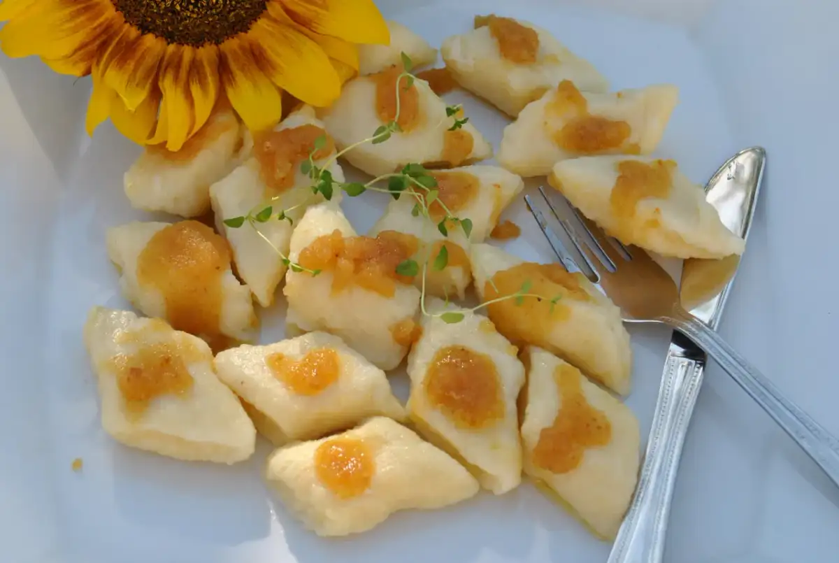 Pyszne, leniwe pierogi z sosem i gałązką tymianku, obok słonecznik.
