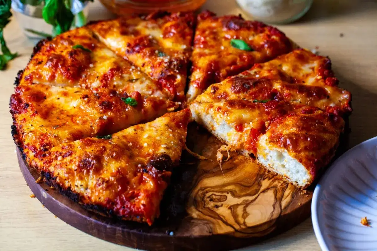 Pyszna pizza rzymska z chrupiącym ciastem, sosem pomidorowym i ciągnącym serem, pokrojona na kawałki.