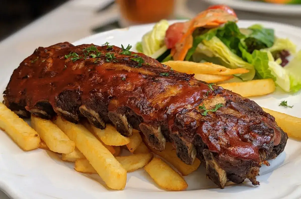 Soczyste żeberka w sosie barbecue, podane z chrupiącymi frytkami i świeżą sałatką. Pyszny obiad gotowy!