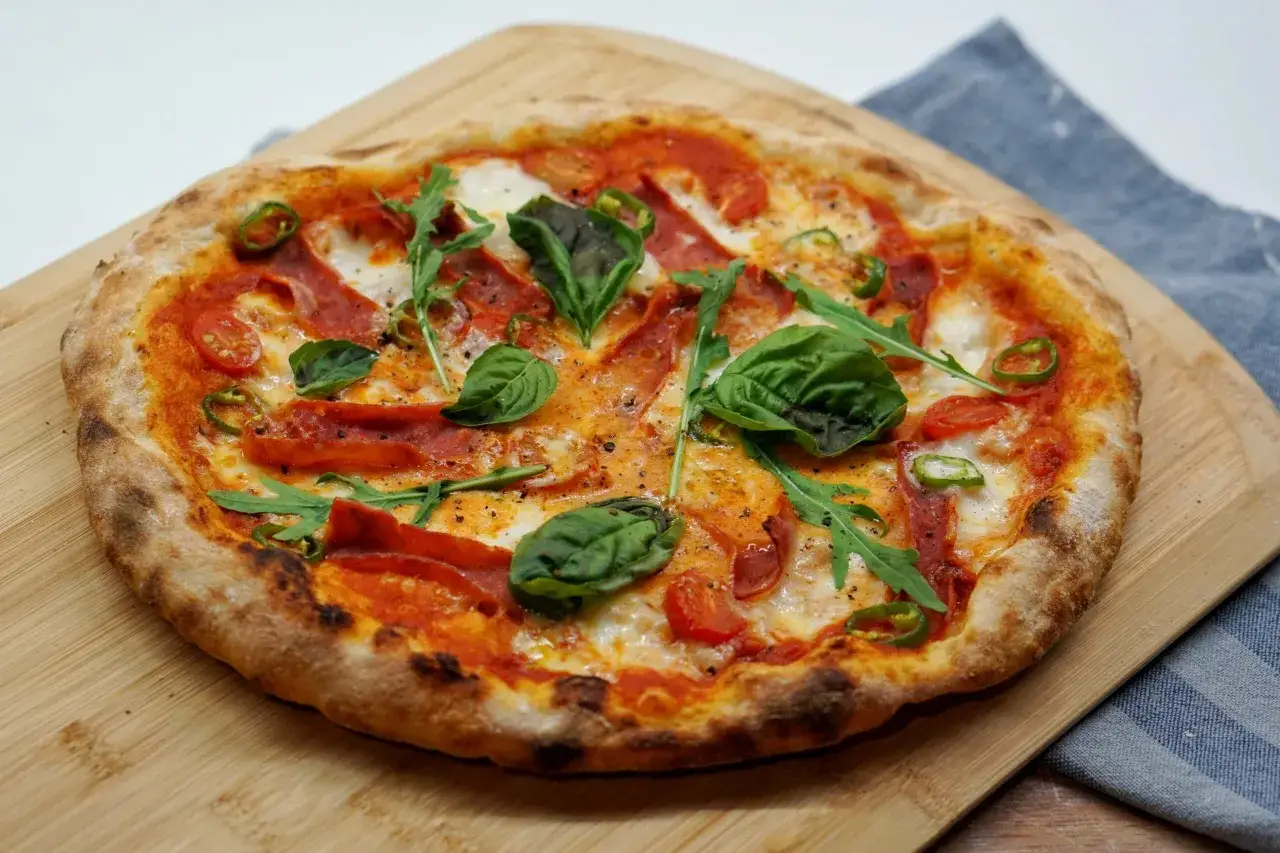Pyszna pizza z pikantnym salami, pomidorkami, rukolą i bazylią. Idealne pizza składniki na wierzch dla miłośników ostrych smaków.
