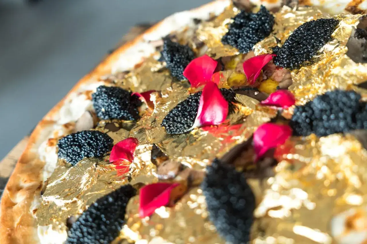 Wykwintna pizza ozdobiona jadalnym złotem, czarnym kawiorem i płatkami róż. To zdecydowanie najdroższa pizza na świecie, prawdziwe dzieło sztuki kulinarnej.