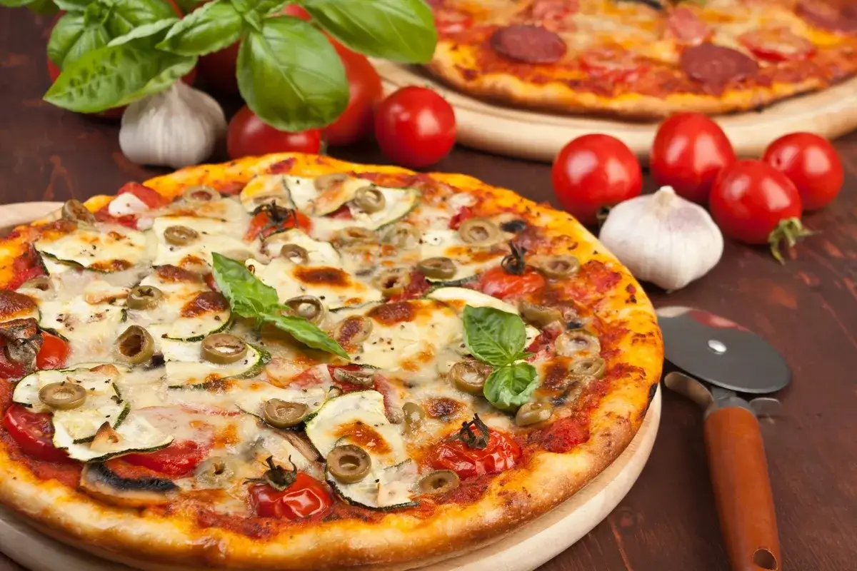 Pizza z cukinią, oliwkami i pomidorkami koktajlowymi. Idealne jakie pieczarki do pizzy? Te na zdjęciu wyglądają pysznie!
