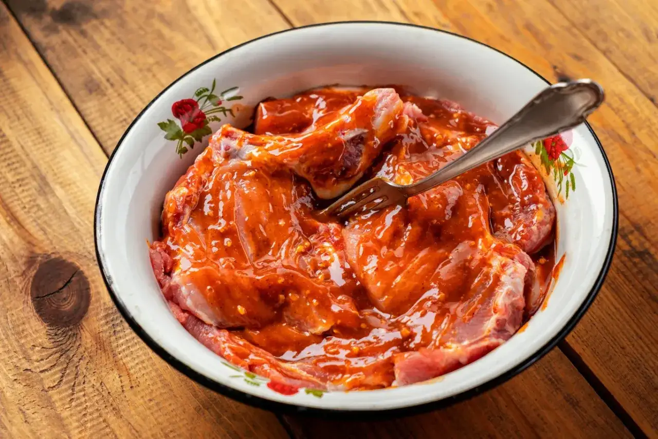 Mięso w misce, gotowe do grillowania. Aromatyczna marynata na grilla otacza soczyste kawałki.