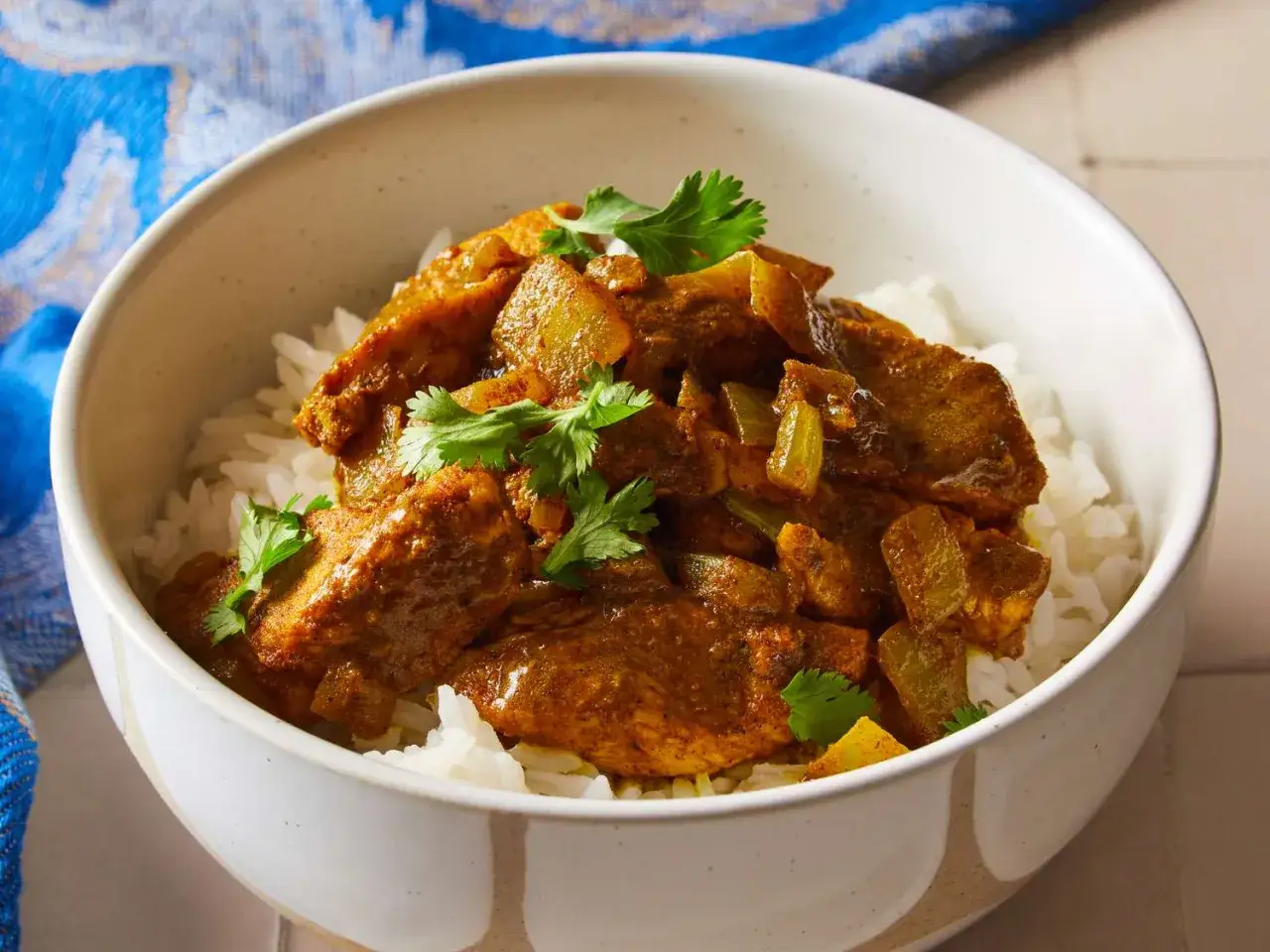 Pyszny kurczak w sosie curry, podany na ryżu, z natką kolendry. Idealny prosty przepis na obiad.