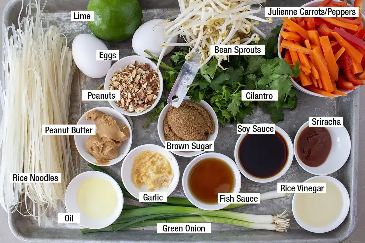 Składniki do sosu pad thai: makaron ryżowy, jajka, orzeszki ziemne, masło orzechowe, fasolka mung, marchewka, kolendra, sos sojowy, brązowy cukier, czosnek, olej, zielona cebulka, sos rybny, ocet ryżowy, sriracha.