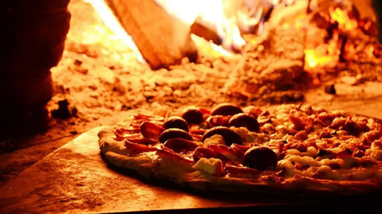 Pizza z oliwkami i serem, pieczona w piecu opalanym drewnem, z dodatkiem pikantnego sosu chipotle.