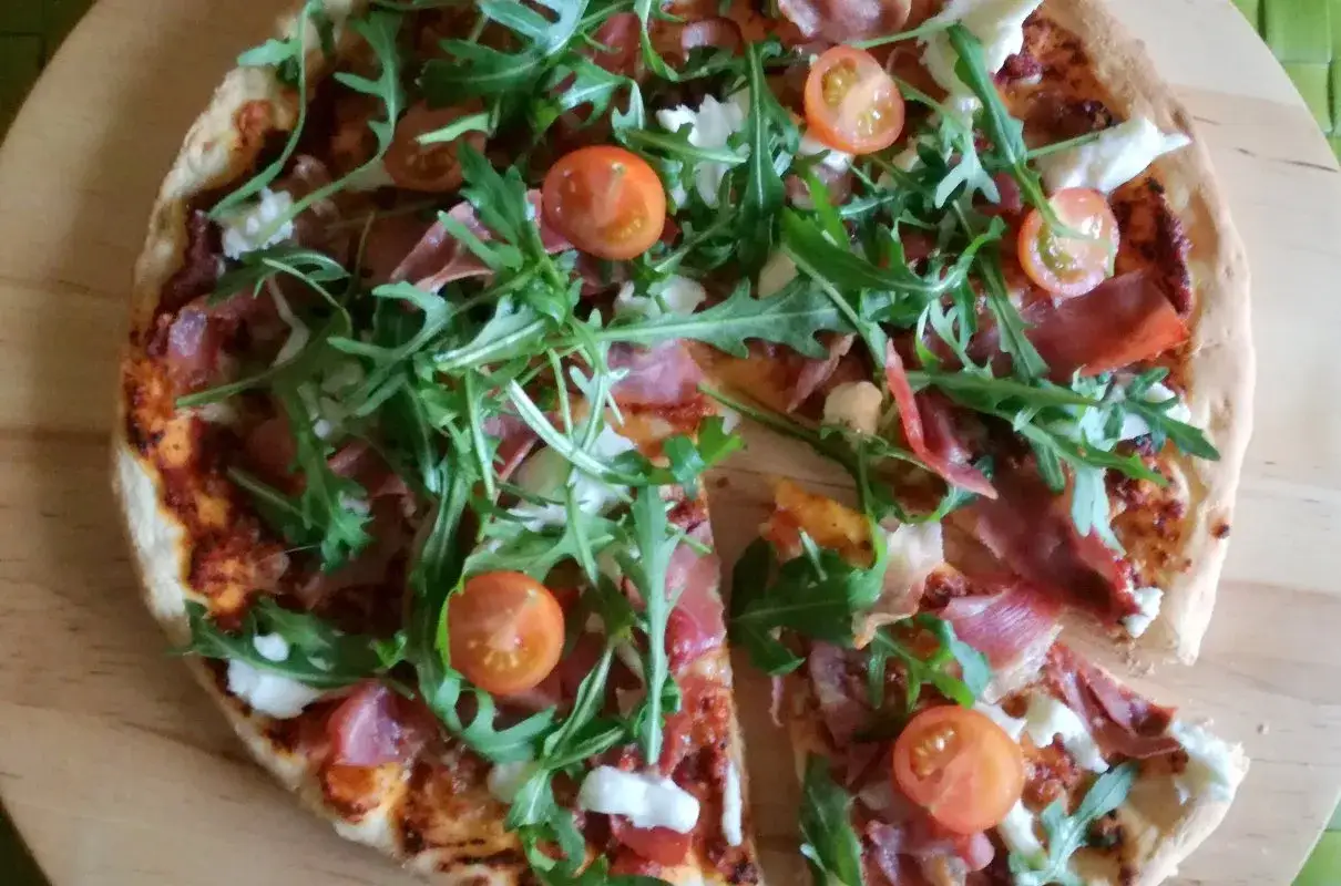Pizza z rukolą, pomidorkami i szynką parmeńską – niezbędny dodatek smakowy włoskiej pizzy.