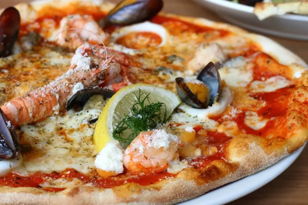 Wykwintna pizza z owocami morza, krewetkami i małżami, ozdobiona cytryną i ziołami. Czy to najdroższa pizza na świecie?