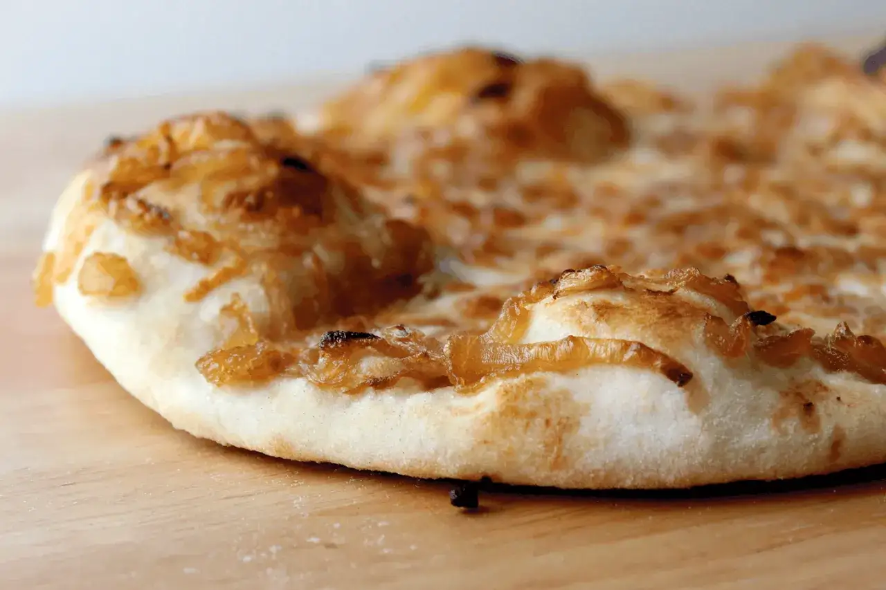 Chrupiąca pizza z karmelizowaną cebulą, której słodycz podkreśla sos cebulowy. Idealna na szybką przekąskę.