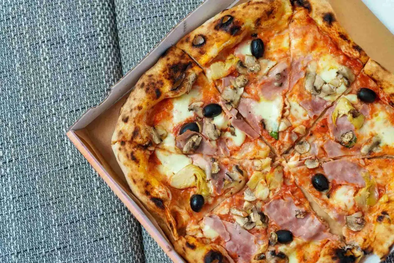 Pyszna pizza capricciosa z szynką, pieczarkami, karczochami i oliwkami, prosto z pieca.