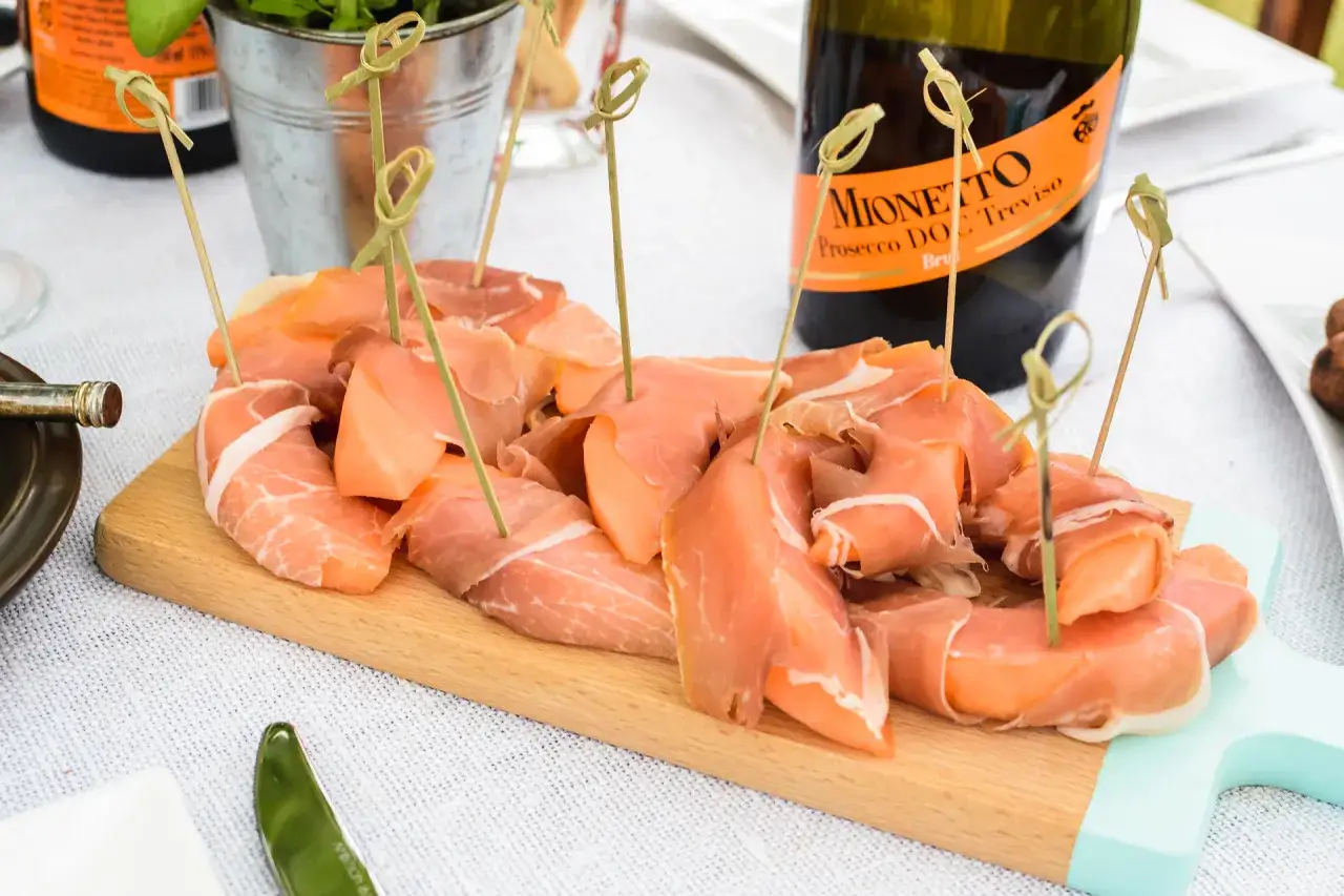 Prosciutto z melonem na desce, idealne na wieczór włoski. Menu uzupełnia butelka Prosecco Mionetto.
