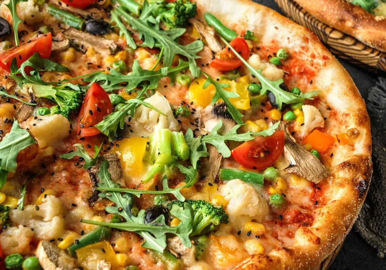 Apetyczna pizza bez mięsa z brokułami, pomidorkami, kukurydzą, papryką i rukolą.