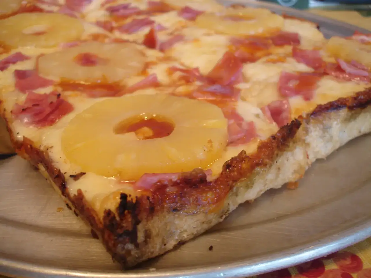 Kto wymyślił pizzę hawajską? Ta pizza z ananasem i szynką na metalowej tacy jest dowodem na to, że pomysły bywają zaskakujące.