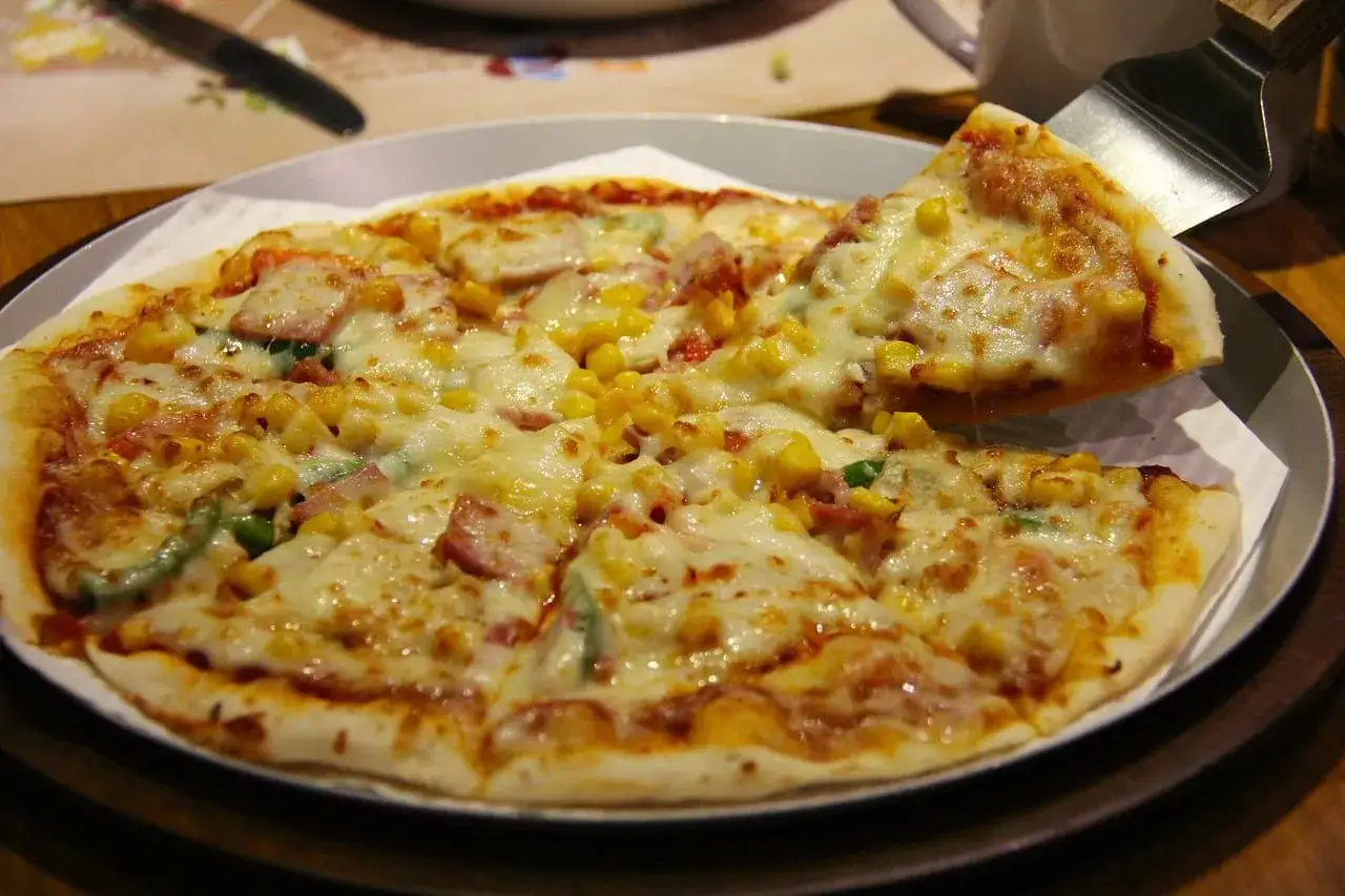 Pyszne pizze z kukurydzą, szynką i zieloną papryką, obficie posypane ciągnącym się serem. Idealne na wspólne spotkanie.