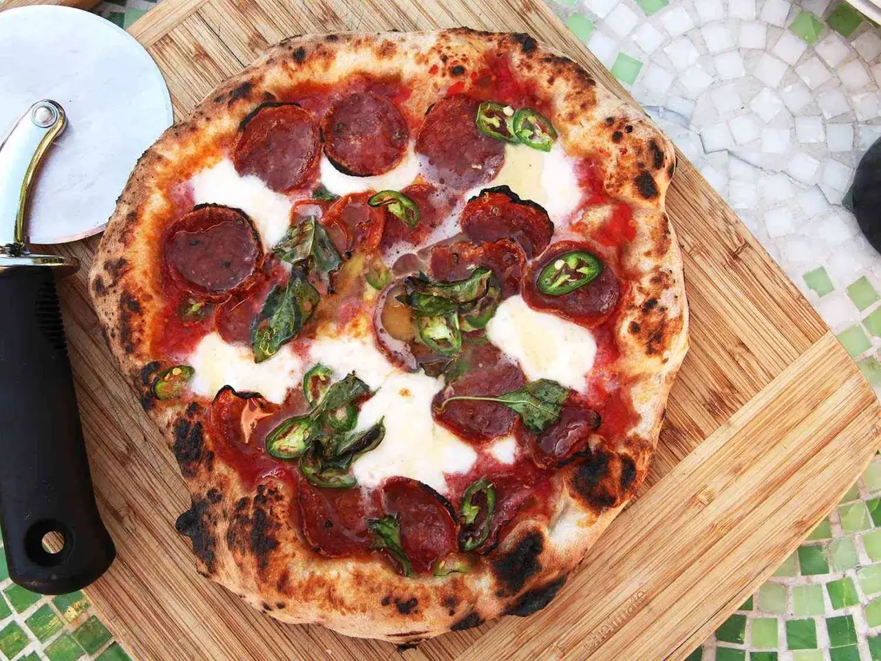 Pikantna pizza diavola z pepperoni, mozzarellą i papryczkami jalapeño, gotowa do pokrojenia.