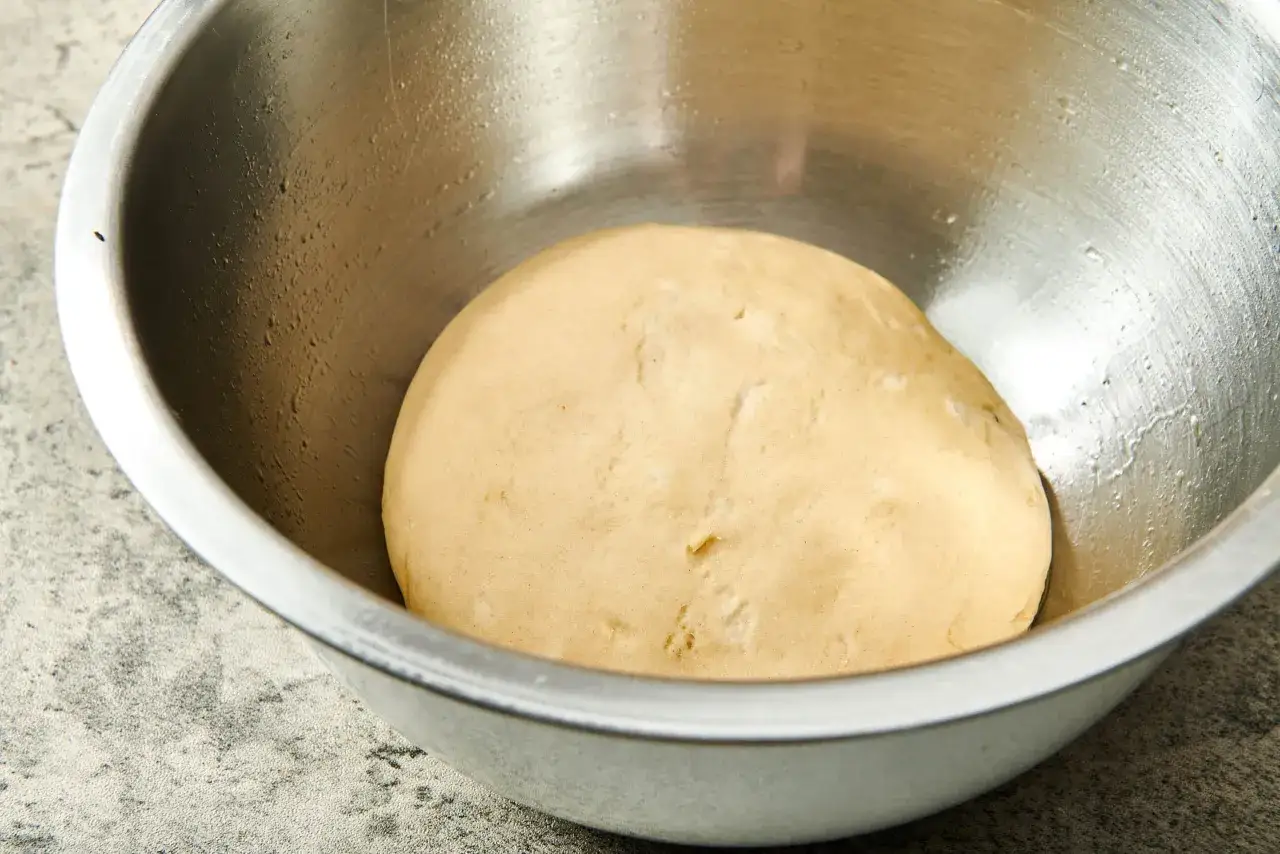 Gotowe ciasto na pizzę w metalowej misce. Idealne na szybki przepis na ciasto do pizzy, gotowe do wyrastania.