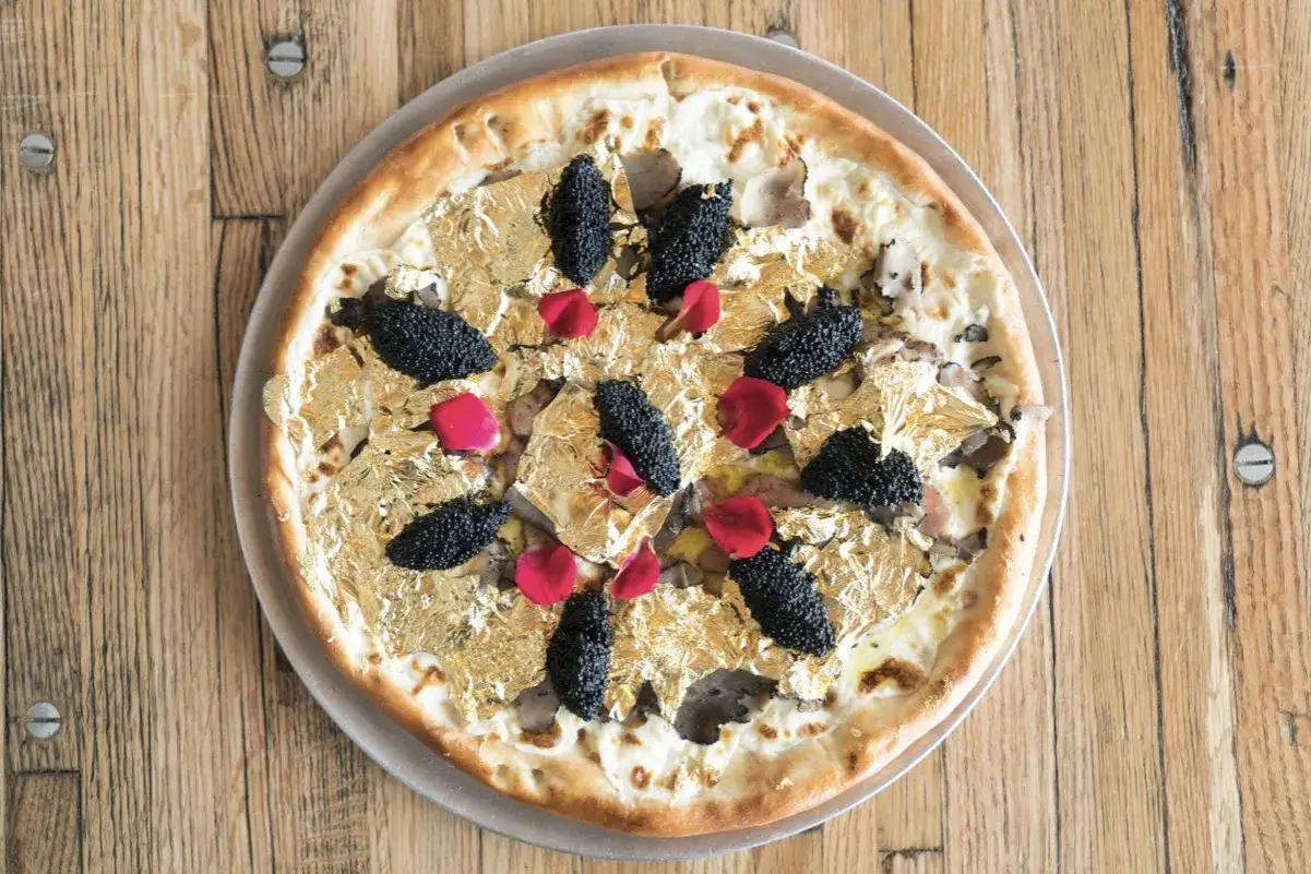 Wykwintna pizza ozdobiona płatkami złota, czarnym kawiorem i płatkami róży. To zdecydowanie najdroższa pizza na świecie, prawdziwe dzieło sztuki kulinarnej.