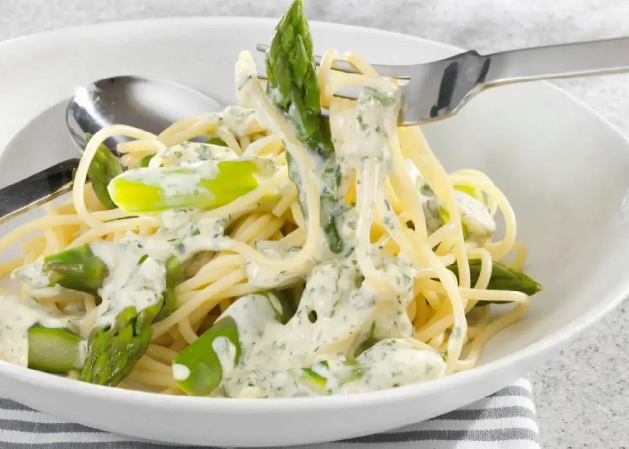 Pyszne spaghetti z zielonymi szparagami w kremowym sosie śmietanowym, posypane ziołami.